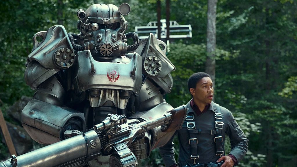 Maximus standing next to a suit of power armor