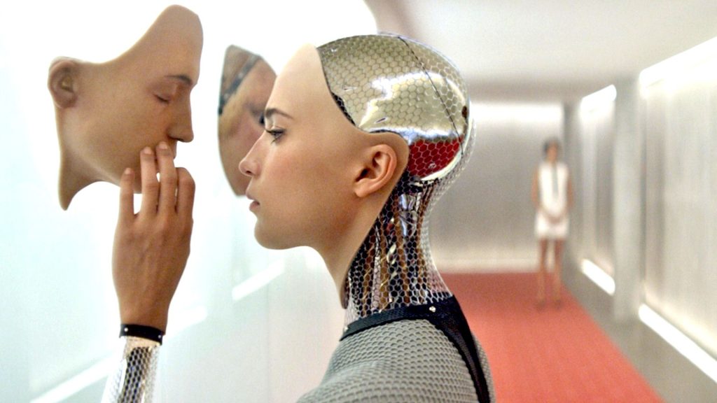3 new to Netflix movies I recommend you watch this weekend (Feb 28–March 1) Alicia Vikander as the robot Ava in the movie Ex Machina touching a fake human face hanging on a white wall.