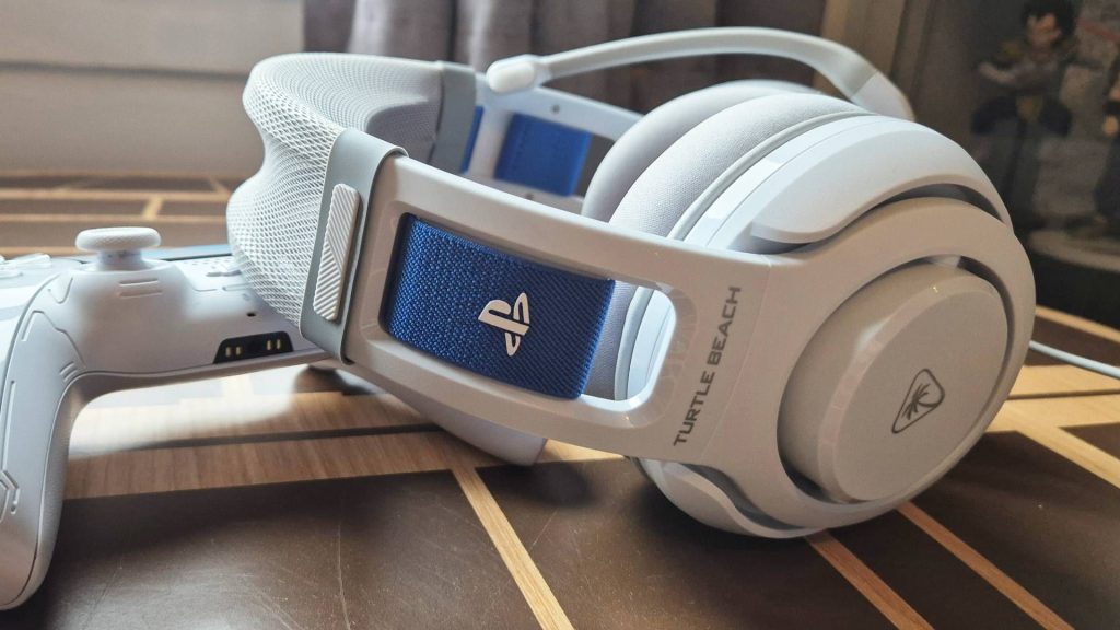 Photo of a white headset sitting on a wooden desk, with a PlayStation logo on its side.