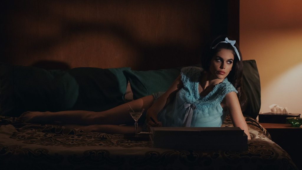 Kaia Gerber as Mitzi, reclining on a sofa, in Palm Royale season 2.