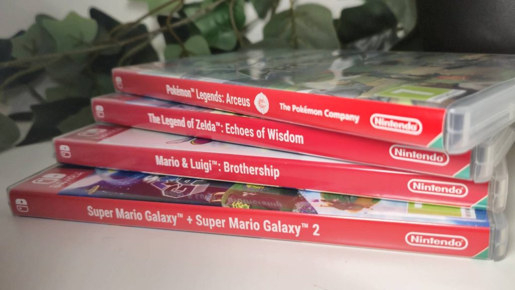 Photo of a pile of Switch games sitting on a white desk.