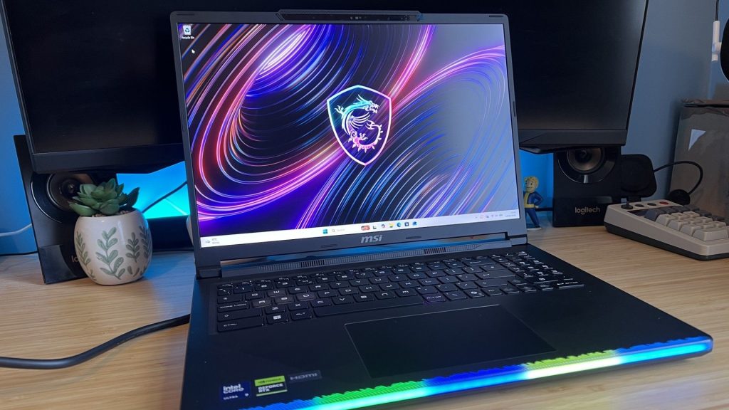 MSI Raider 16 Max gaming laptop on a wooden desk with blue backlighting