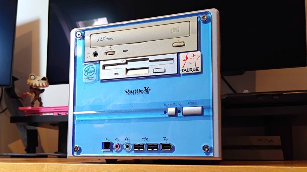 Shuttle XPC from 2001 at an angle with blue front plate sitting on woodgrain surface.